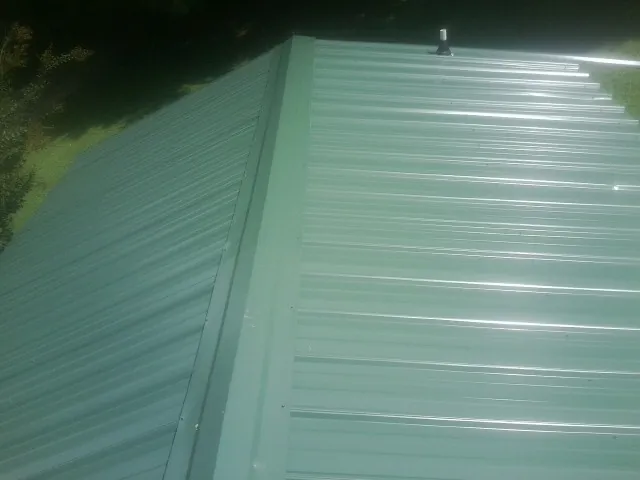 New green metal panels meeting at the ridge of a roof — Flat Roof Repair work by our crew in Wisconsin Dells