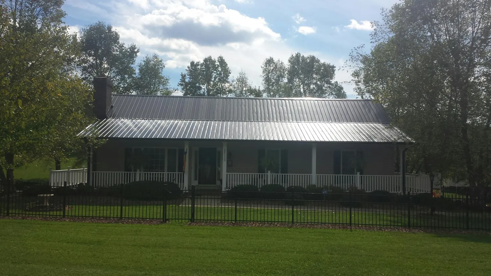 Gray metal roof on a brick ranch with a full width front porch — Gutter Guard Installation work by our crew in Wisconsin Dells