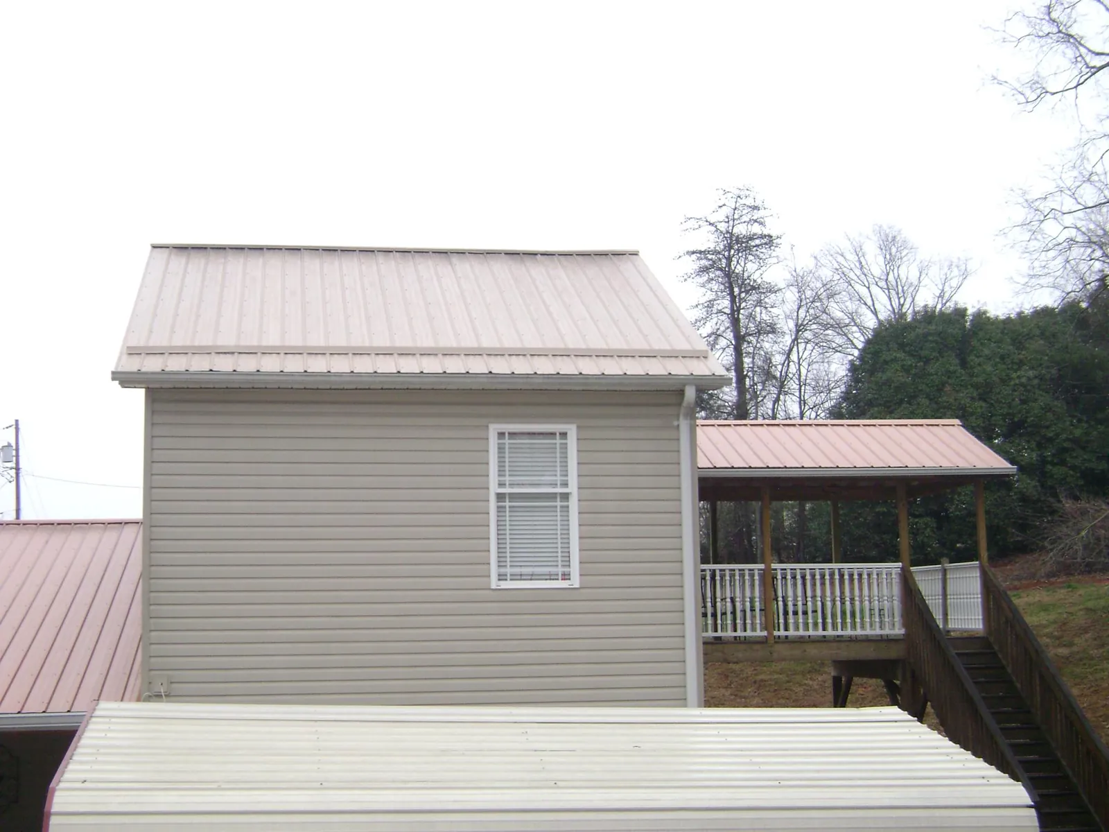 Tan metal roofs on a two story addition and attached porch, from a Roof Replacement job in Wisconsin Dells