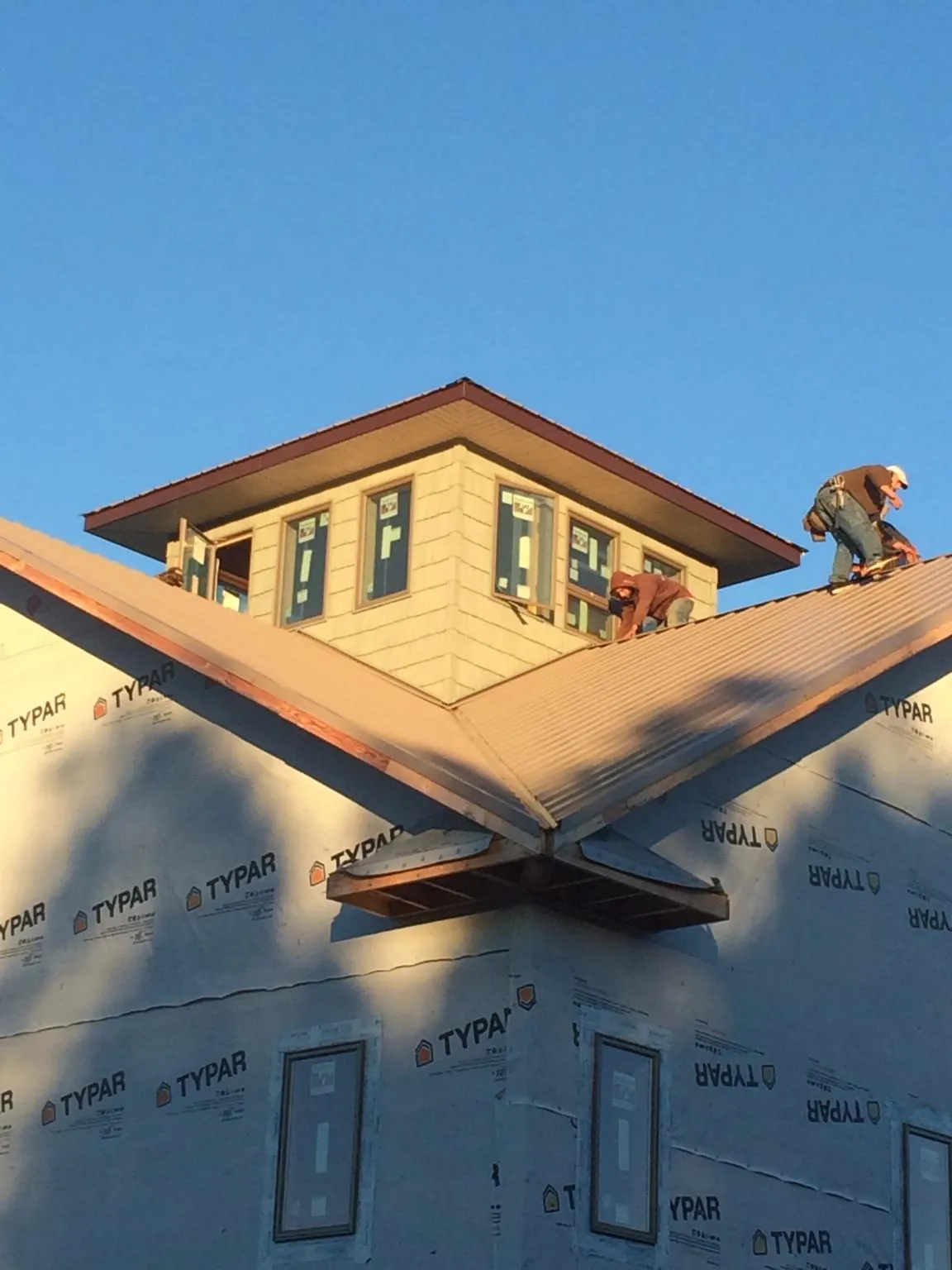Roofers working around a rooftop cupola on a new metal roof at sunset — Roof Waterproofing in Wisconsin Dells by Roofing Brothers